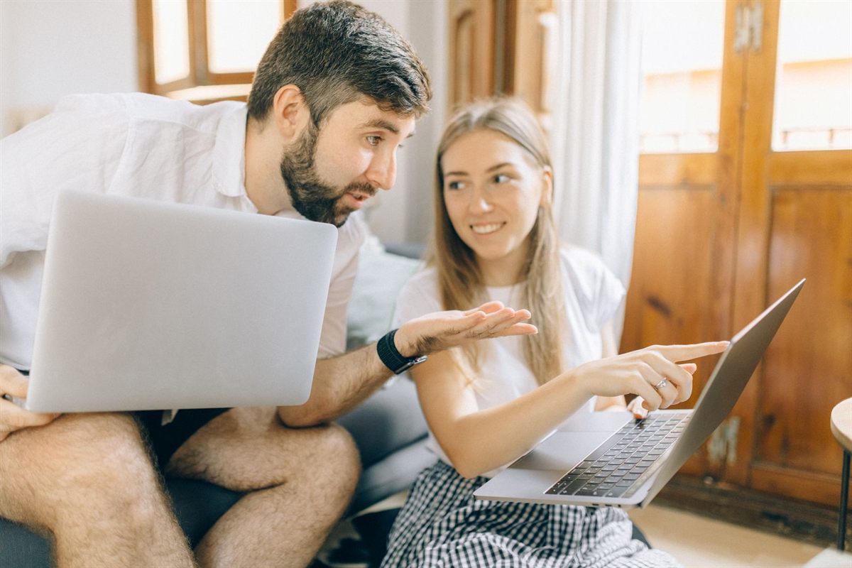 A couple comparing trip options on two laptops at home