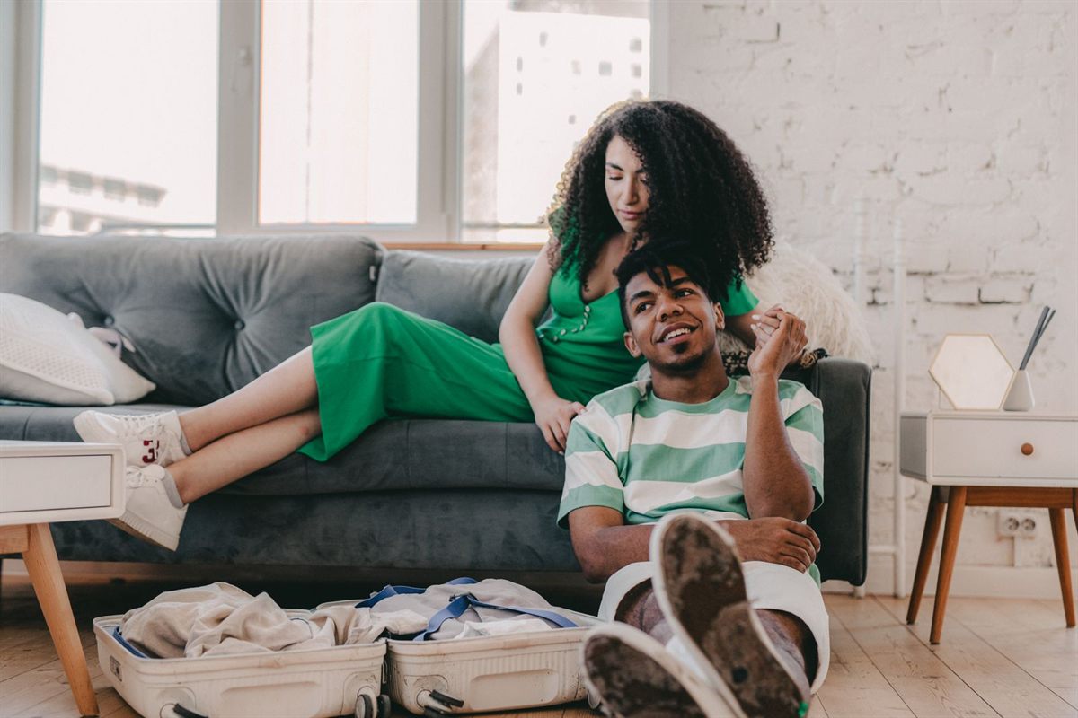 A couple relaxing at home with a packed suitcase on the floor after a trip