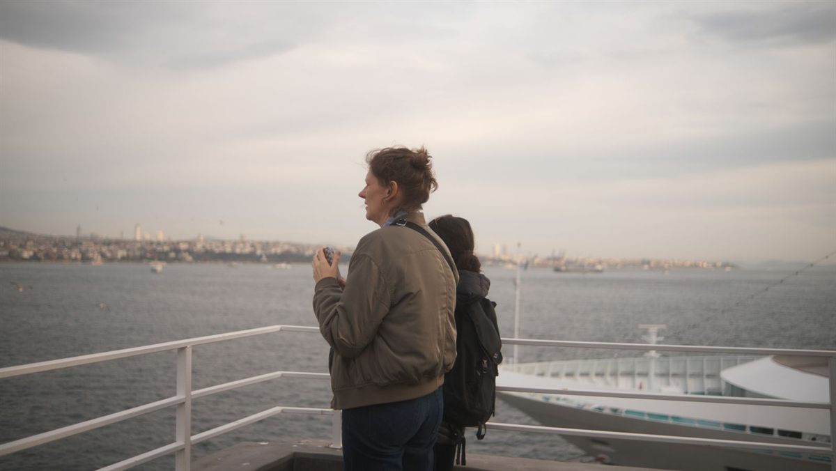Two travellers looking out over the water from a ship deck on a cloudy day