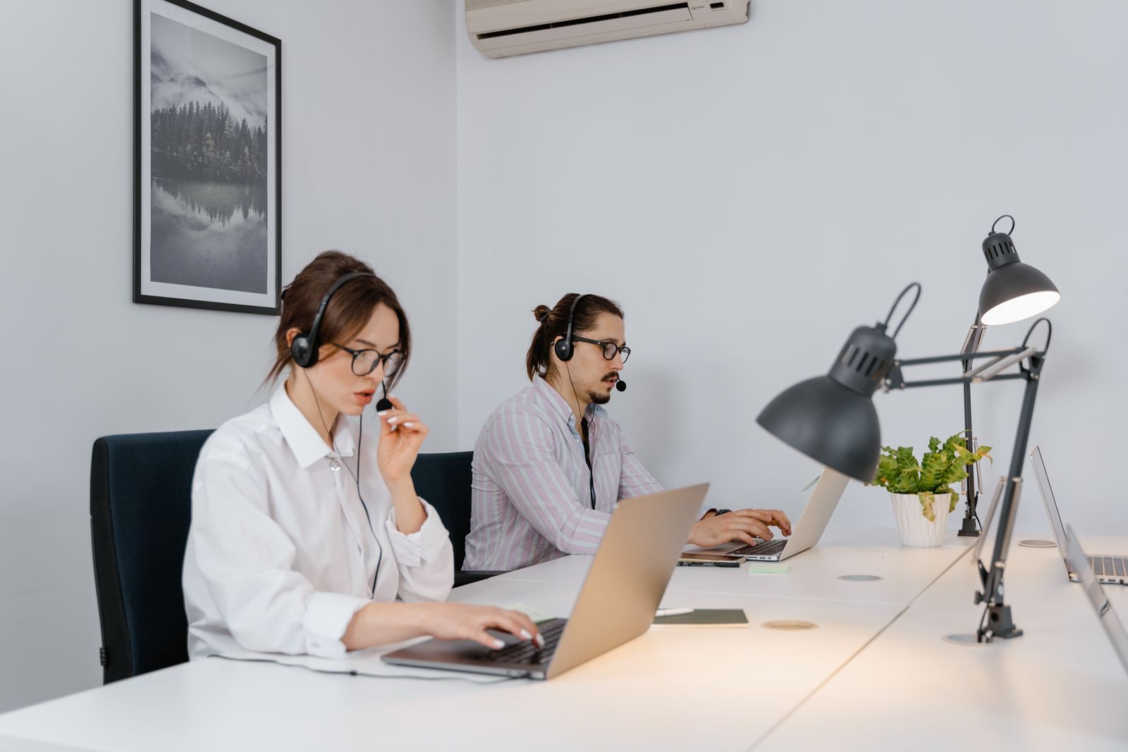 Two sales agents with headsets working at laptops, like a cruise line personal vacation planner team