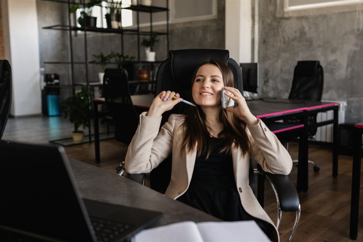 A smiling woman taking a phone call in a modern office