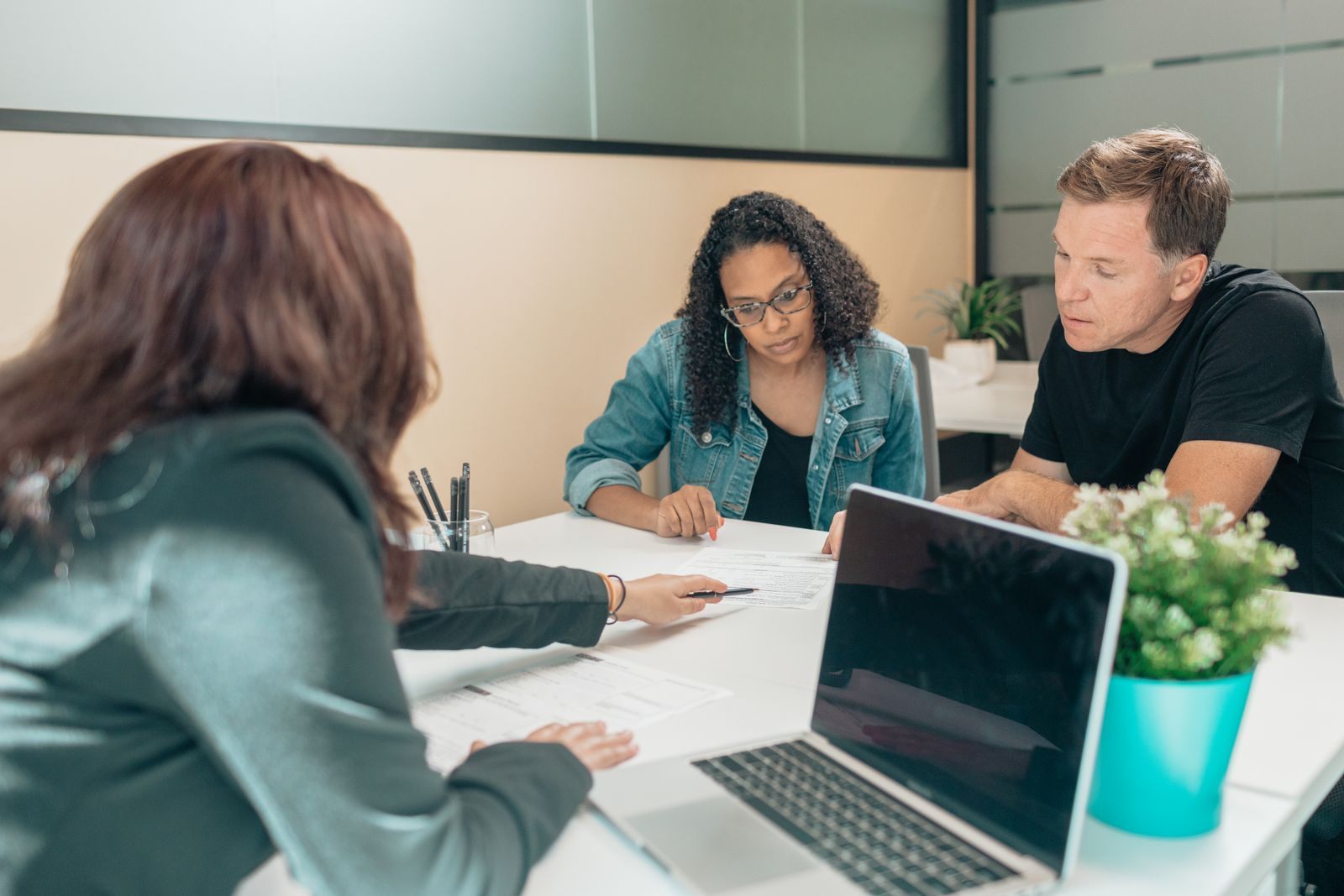A couple meeting an advisor at an office table with a laptop, the first stage of planning a cruise